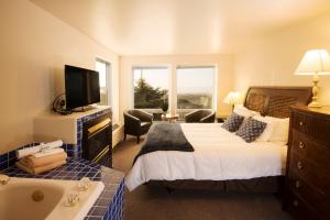 um quarto com uma cama, uma banheira e uma televisão em The Seaside Oceanfront Inn em Seaside