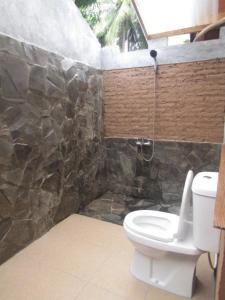 a bathroom with a toilet and a rock wall at Bale Jukung in Tanjung