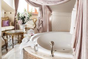 een badkamer met een bad en een tafel met bloemen bij Dwór Prezydencki Boutique Hotel & SPA in Tarnów