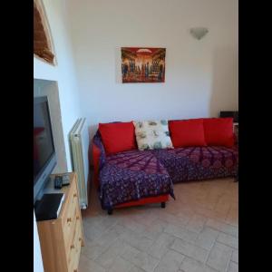 ein Wohnzimmer mit einem Sofa und einem TV in der Unterkunft Casetta alla Caduta in San Vincenzo