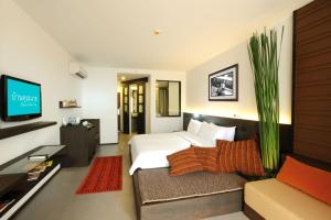 a bedroom with a bed and a couch and a tv at Baan Khun Nine in Pattaya