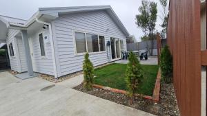 a white house with a yard with trees in front of it at Brand New Home - Central Masterton in Masterton
