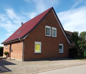a brick house with a red roof and a yellow window at Ferienwohnung-Tomme in Wulfen auf Fehmarn
