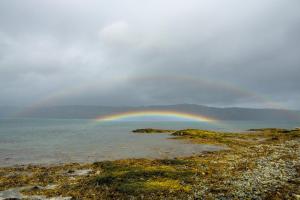 a sunset on a beach with a rainbow in the sky at Isle Of Mull Hotel and Spa in Craignure