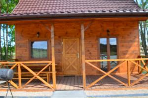 a log cabin with a porch and two doors at Pod Dębem in Winnica