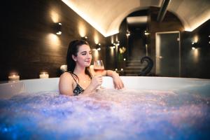 a woman sitting in a bath tub holding a glass of wine at Penzion U Hada in Velké Pavlovice