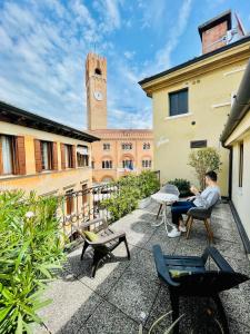 a man sitting in a chair on a courtyard with a clock tower at Palazzina300 in Treviso