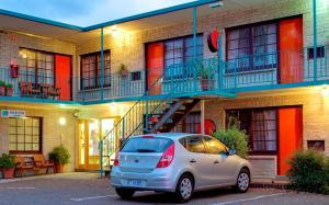 un coche aparcado en un aparcamiento frente a un edificio en Martin Cash Motel, en Hobart