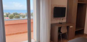 a room with a view of a balcony with a television at Hotel Corallo in Fregene