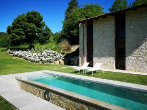 a swimming pool in a yard with two chairs and a house at Molino dei Ciliegi - Splendida villa in Umbria in San Venanzo