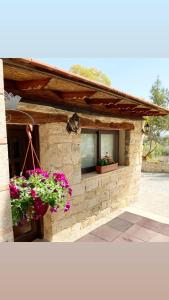a stone building with flowers in a window at Cosmema house 2 Studio with great mountain view in Stroumbi