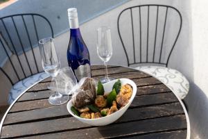 un tavolo con una ciotola di cibo e una bottiglia di vino di Apartmani Velnic a Baška