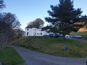 a white house on top of a hill with a tree at Clunebeg Lodge in Drumnadrochit