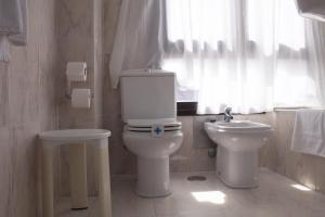 a white bathroom with a toilet and a sink at Hotel Ezeiza in Donostia-San Sebastián
