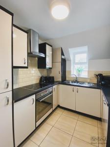 a kitchen with white cabinets and black counter tops at Manor Apartments in Bournemouth