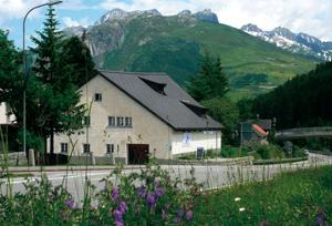 a white house with a black roof on a mountain at Jugendherberge Hospental in Hospental