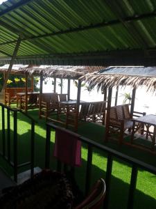 Un grupo de mesas y sillas bajo un techo. en Boat house marina restaraunt and homestay, en Suratthani