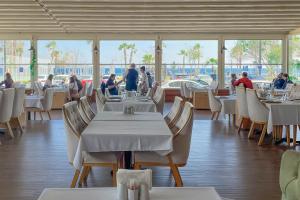 安塔利亞的住宿－水晶海濱酒店，一间设有白色桌椅的餐厅,供有饭吃的人用餐