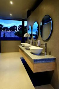 a bathroom with four sinks and two mirrors at Kambaniru Beach Hotel and Resort in Waingapu