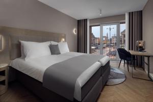 um quarto de hotel com uma cama, uma secretária e uma janela em The Market Hotel em Groningen