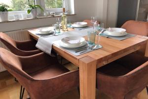 una mesa de madera con sillas, platos y copas de vino en Komfortferienwohnung Harzglueck auf 2 Etagen, en Hohegeiss