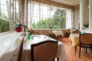 a restaurant with tables and chairs and large windows at Kurvilla am Park in Bad Kissingen