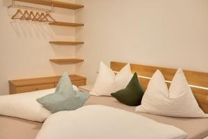 Una cama con almohadas blancas y verdes. en Glögglhof en Lana