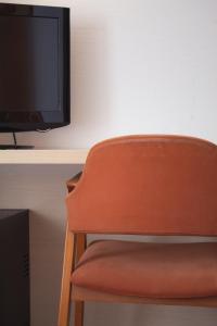 an orange chair in front of a desk with a television at Hotel Ezeiza in San Sebastián