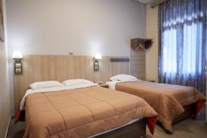 2 Betten in einem Hotelzimmer neben einem Fenster in der Unterkunft Amalia City Rooms in Chios