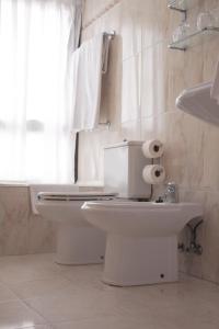 a white bathroom with a toilet and a sink at Hotel Ezeiza in San Sebastián