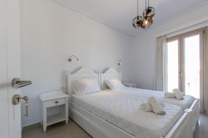 a white bedroom with a white bed and a window at Evdokia in Plaka