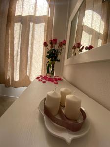 zwei Kerzen auf einem Tisch mit einer Vase Rosen in der Unterkunft Suite Saffi 99 in Viterbo