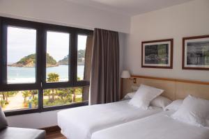 a hotel room with two beds and a large window at Hotel Ezeiza in San Sebastián