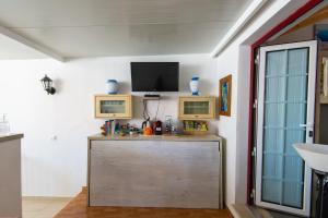 a room with a television and a wooden cabinet at GreenEscapes I in Porto Covo