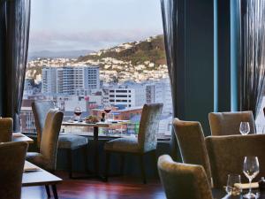 惠灵顿Mövenpick Hotel Wellington的餐厅设有椅子和桌子及酒杯