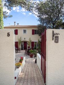 a courtyard of a house with a gate and a patio at Les Jardins d'Holi appartement proche Uzès in Garrigues-et-Sainte-Eulalie +12 photos