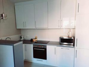 ビャウィストクにあるMalmeda 31Aの白いキャビネットと黒い電子レンジ付きのキッチンが備わります。 +1枚の写真
