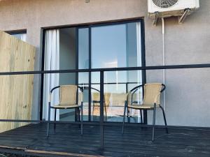 2 Stühle und ein Tisch auf einem Balkon mit Fenstern in der Unterkunft PLC Hotel Centenario in Paso de los Toros