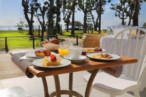 uma mesa de madeira com comida e bebidas para o pequeno-almoço em Hotel Restaurant San Lucianu em Moriani Plage