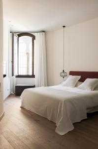 - une chambre blanche avec un grand lit et une fenêtre dans l'établissement La Ermita Suites - Único Hotel Monumento de Córdoba, à Cordoue