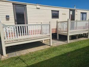 a mobile home with a porch and two benches at 6 Berth Panel heated on Sealands Baysdale in Ingoldmells