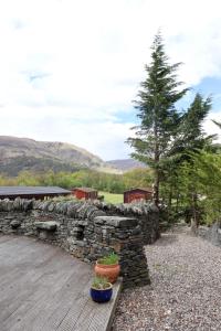 a stone wall and two potted plants on a wooden deck at Lodge 38 Rowardennan , Loch Lomond in Glasgow