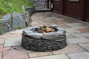 uma fogueira de pedra em frente a uma casa em Lodge 38 Rowardennan , Loch Lomond em Glasgow