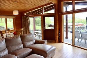 a living room with a leather couch and a porch at Lodge 38 Rowardennan , Loch Lomond in Glasgow