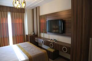 ein Hotelzimmer mit einem Bett und einem Flachbild-TV in der Unterkunft Burçman Hotel Vişne in Yıldırım
