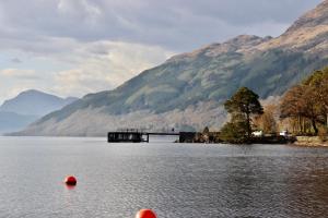 a lake with a bridge and mountains in the background at Rowardennan Hotel in Rowardennan