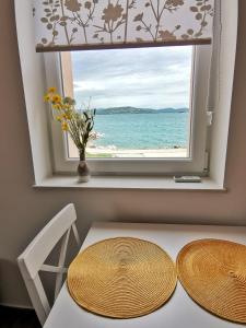 uma mesa com duas cadeiras e uma janela com vista para o oceano em Apartment Roman em Betina