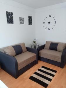 a living room with two couches and a clock on the wall at merRelax Apartman in Miskolc