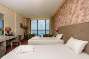 a hotel room with two beds and a desk at The Grand Gloria Hotel in Batumi