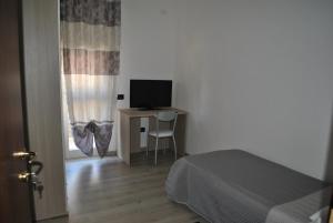 ein Schlafzimmer mit einem Bett und einem Schreibtisch mit Fernseher in der Unterkunft Raxul Room in Sestu